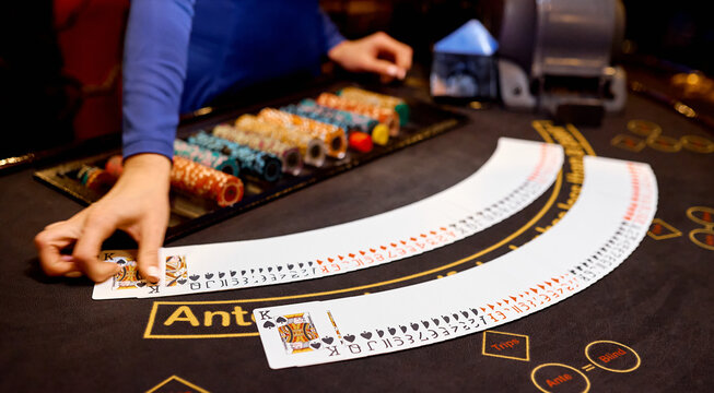 croupier on the poker table with a brown cloth lays the card chips between his hands