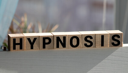 Hypnosis word written on wood cube with red background