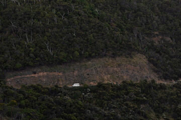 White mini van traveling alongside cliff edge Great Ocean Road, Victoria, Australia.