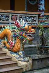 Colorful dragon sculpture at the entrance to a Buddhist temple on the steps in the city of Danang,...