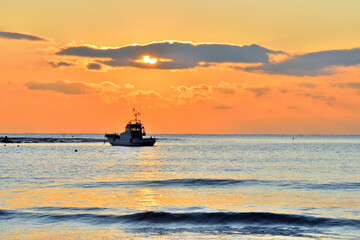 夕日が沈む材木座海岸に浮かぶ漁船