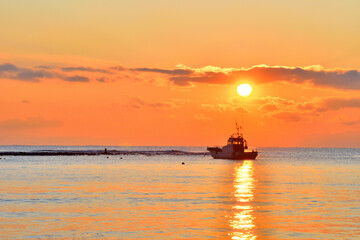 夕日が沈む材木座海岸に浮かぶ漁船