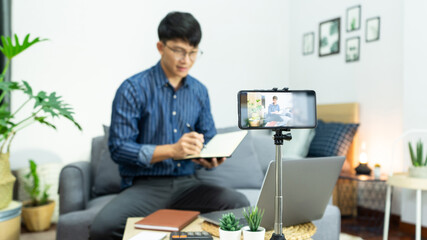 Asian blogger recording vlog video on camera review of product at home office