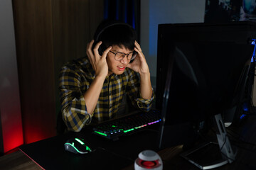 Fototapeta na wymiar Asian man cyber sport gamer concentrated playing video games on computer eSport concept