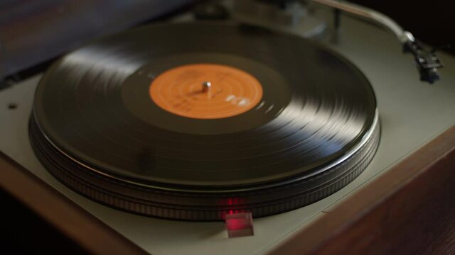 A vinyl record gets placed on a turntable and starts listening to music