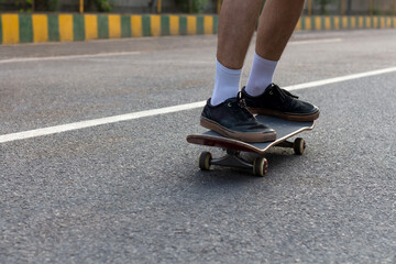 Closeup shot of someone's feet who is cruising on a skateboard on an empty road.  © Sausinbis