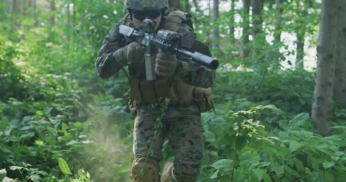 Portrait of soldier in uniform in dense forest ready for military action