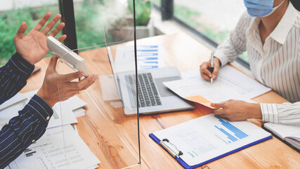 business team working hard by the plastic protective wall, concept of social distancing to prevent the spread of coronavirus COVID-19
