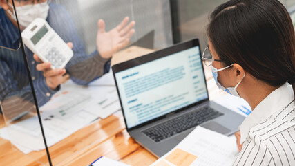 business team working hard by the plastic protective wall, concept of social distancing to prevent the spread of coronavirus COVID-19

