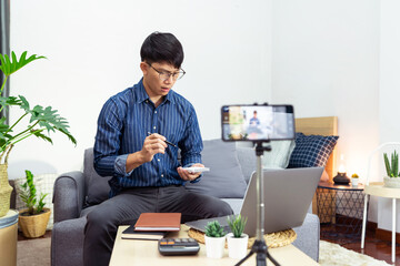 Asian blogger recording vlog video on camera review of product at home office