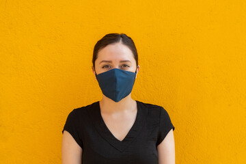 Woman wearing a pink facemask, front shoot, outdoors with bright yellow background