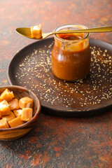 Jar and bowl with sweet caramel on table