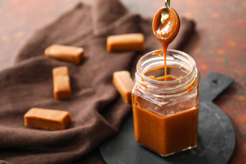 Jar with liquid caramel on table