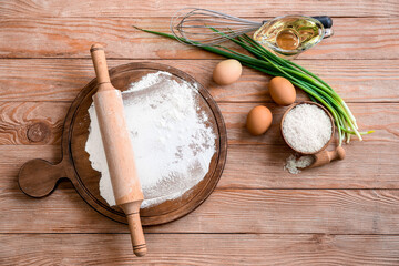 Board with rolling pin, rice flour and products on wooden table