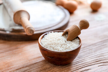 Bowl with rice and scoop on table