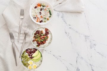 Bowls with tasty rice, beans and vegetables on table