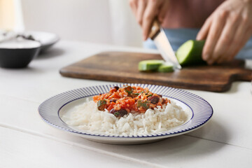Plate with tasty rice, beans and vegetables on table