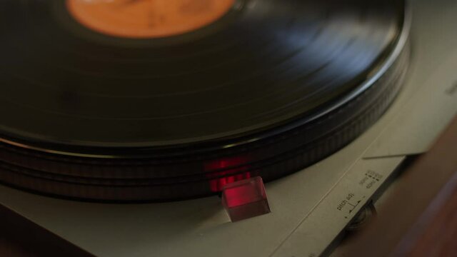 Close up of a vinyl record getting put on a turntable and starting to spin