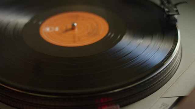 Close up of a vinyl record getting put on a turntable and starting to spin and play music