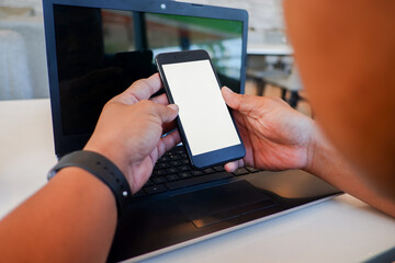 Cropped shot view of man’s Hands hold the smartphone with blank copy space screen for your information content or text message on the gray granite at the modern place.
