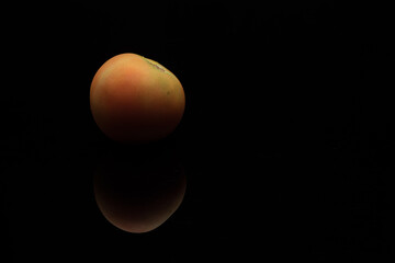 A tomato over dark surface
