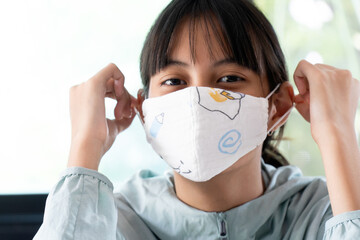 Girl under cotton face mask covering mouth and nose.  Corona Virus or COVID-19 concept.