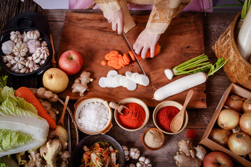 Girl wearing hanbok, making chopped kimchi, radish and carrots to mix with Chinese cabbage. Korean food concept from folk wisdom
