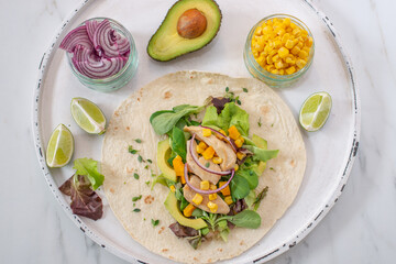 Fresh tortilla wraps with chicken, mushrooms and fresh vegetables on wooden board