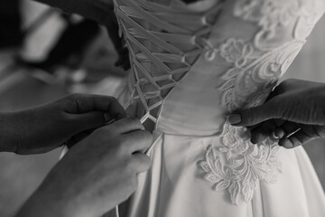 the bride is helped to wear a wedding dress. hands close-up. black white photo - Powered by Adobe