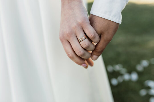 bride and groom holding hands. wedding rings