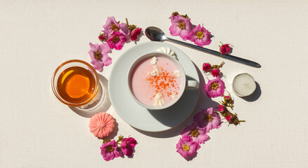 A Cup of pink moon milk with spices, rose flowers and honey and meringues. Top view with space