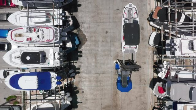 Over head view on forklift smoothly towing the yacht on the multi-level boat parking. Beautiful slow motion drone video for yacht business. 4K aerial video of water transportation, Miami port, Florida