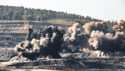 Explosive works on open pit coal mine industry. Dust and puffs of smoke in sky, blasted soil