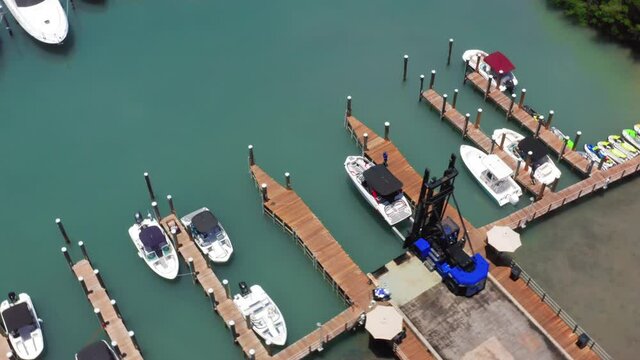 Circular drone view on the marine pier at the Miami harbor. Elevator slowly launching the white yacht to the green water. Beautiful 4K aerial video of water transportation. Marina port, USA