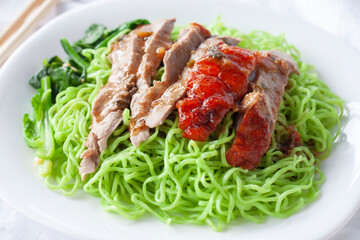 Closeup roasted duck with jade noodles in white plate.