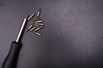 A screwdriver and bits over dark surface,high angle shot