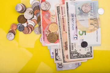 Spreads of bank notes and coins,isolated over yellow