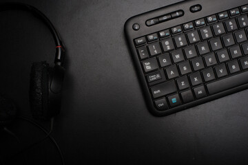 Obraz na płótnie Canvas A keyboard,headphone and a mobile phone over dark background,low key high angle shot