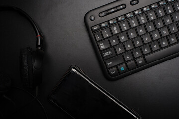 A keyboard,headphone and a mobile phone over dark background,low key high angle shot