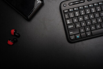 A keyboard,headphone and a mobile phone over dark background,low key high angle shot