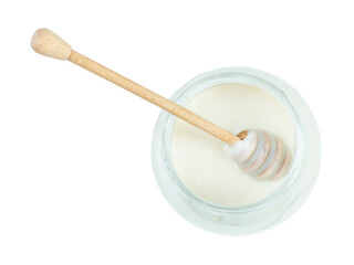 top view of wooden stick on surface of natural organic white honey in glass jar isolated on white background