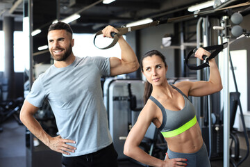 Fototapeta na wymiar Young couple on body training with trx in gym.