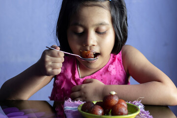 an Indian girl eating gulab jamun