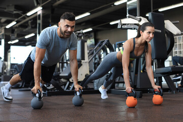 Fototapeta na wymiar Sporty man and woman doing push-up in a gym.