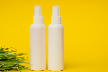 white plastic cosmetic jars and cream on a yellow background