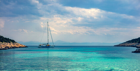 Fototapeta na wymiar Sailing boat at distant remote island paradise with exotical vivid colors.