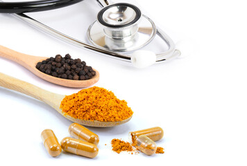 Curcuma capsules, Curcumin powder, Turmeric slices and black pepper (peppercorn ) with medical stethoscope isolated on white background.