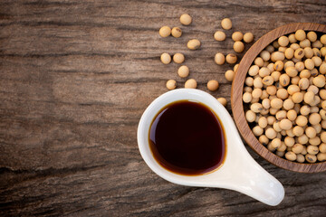 Tasty soy sauce and soybeans in ceramic and wooden bowl isolated on rustic wood table background....