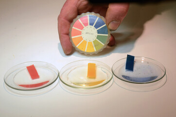 Universal indicator strips for pH value are shown in use on an alcaline solution with pH=14. To the...