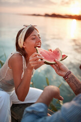 tattooed man feeding his girlfriend with slice of watermelon